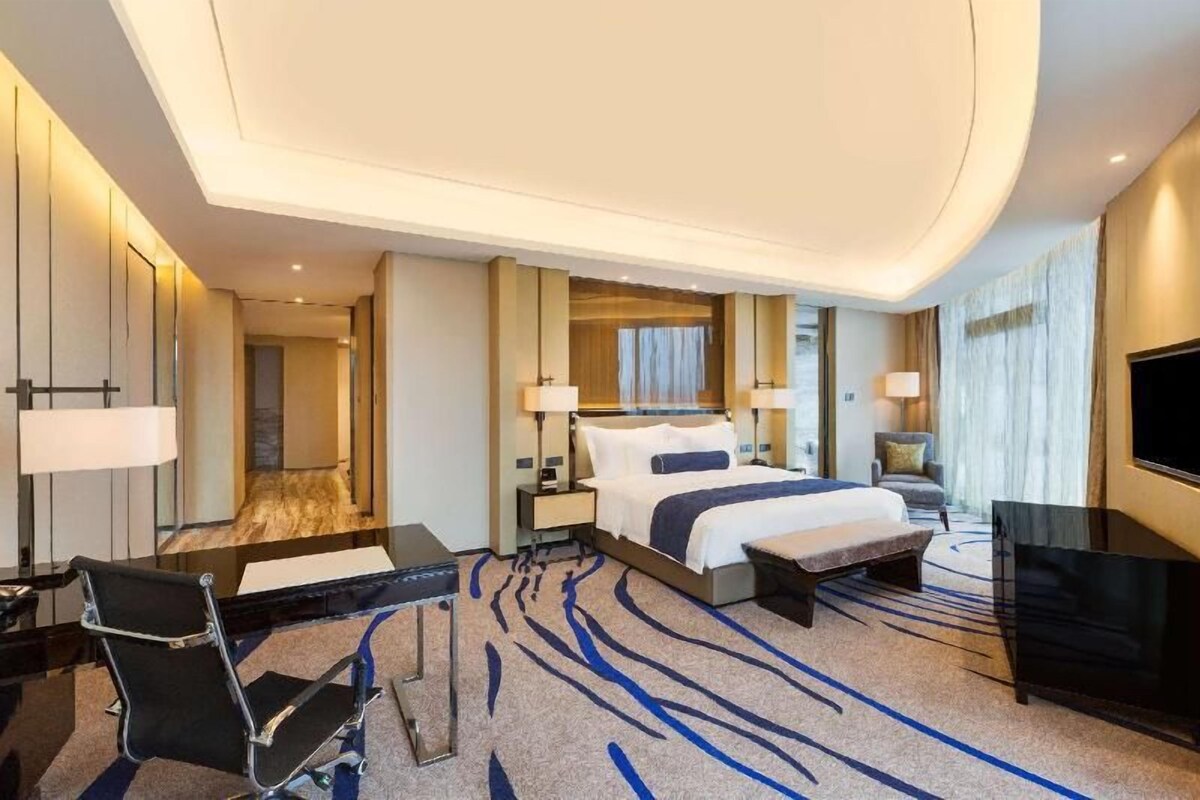 Une chambre d’hôtel comprenant un lit, des tables de chevet, une télévision, un bureau et une chaise.