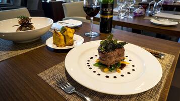 Uma mesa de jantar com um prato de comida, uma garrafa de vinho e uma taça de vinho.