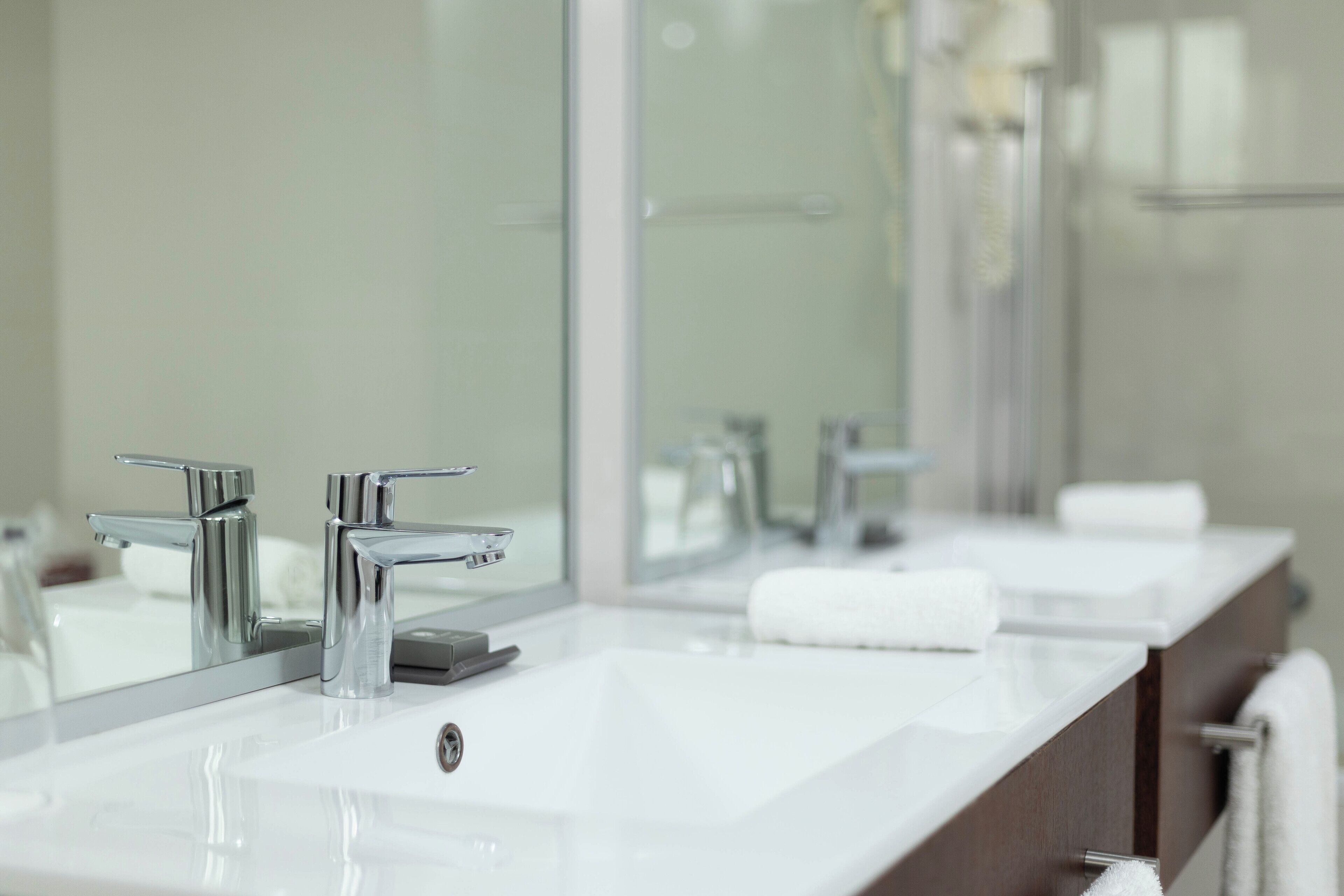 A modern bathroom with two sinks, a large mirror, and a towel rack.
