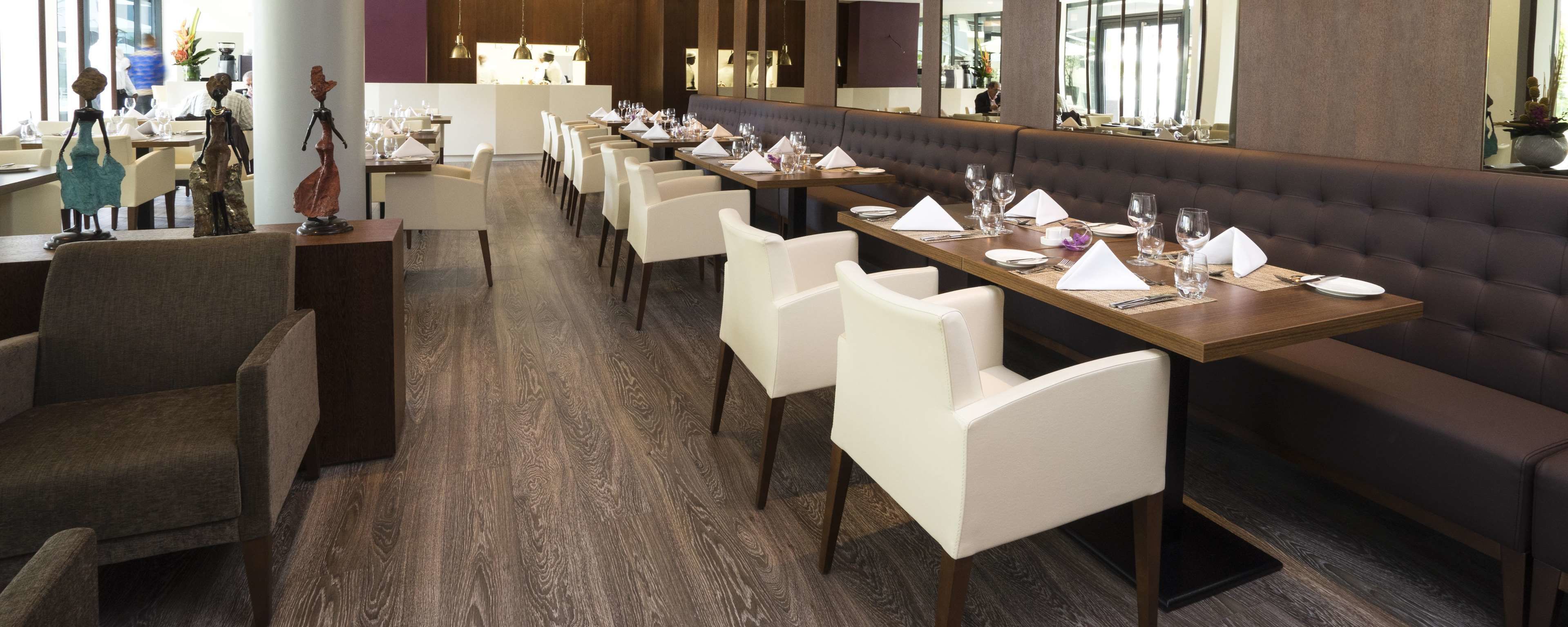 Een restaurant met lange tafels gedekt voor een maaltijd, een centraal zitgedeelte en een modern interieur.