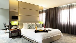 A hotel room with a large bed, a bedside table with a lamp, a tray with snacks and a drink, and a TV on the wall. - Fiesta Residences Boutique Hotel and Serviced Apartments (Accra)