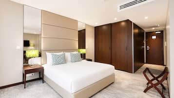 A modern hotel room with a large bed, a bedside table with lamps, a wardrobe, and a chair.
