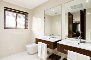 A modern bathroom with two sinks, a toilet, and a large mirror.