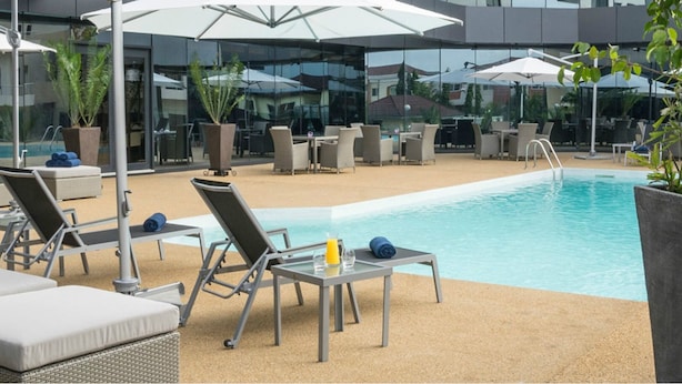 A poolside area with lounge chairs, umbrellas, and a pool. - Fiesta Residences Boutique Hotel and Serviced Apartments (Accra)