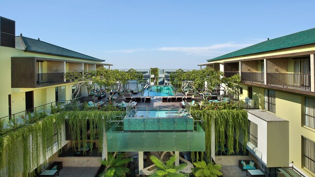 Un hotel con piscina central, zonas de estar al aire libre y balcones.
