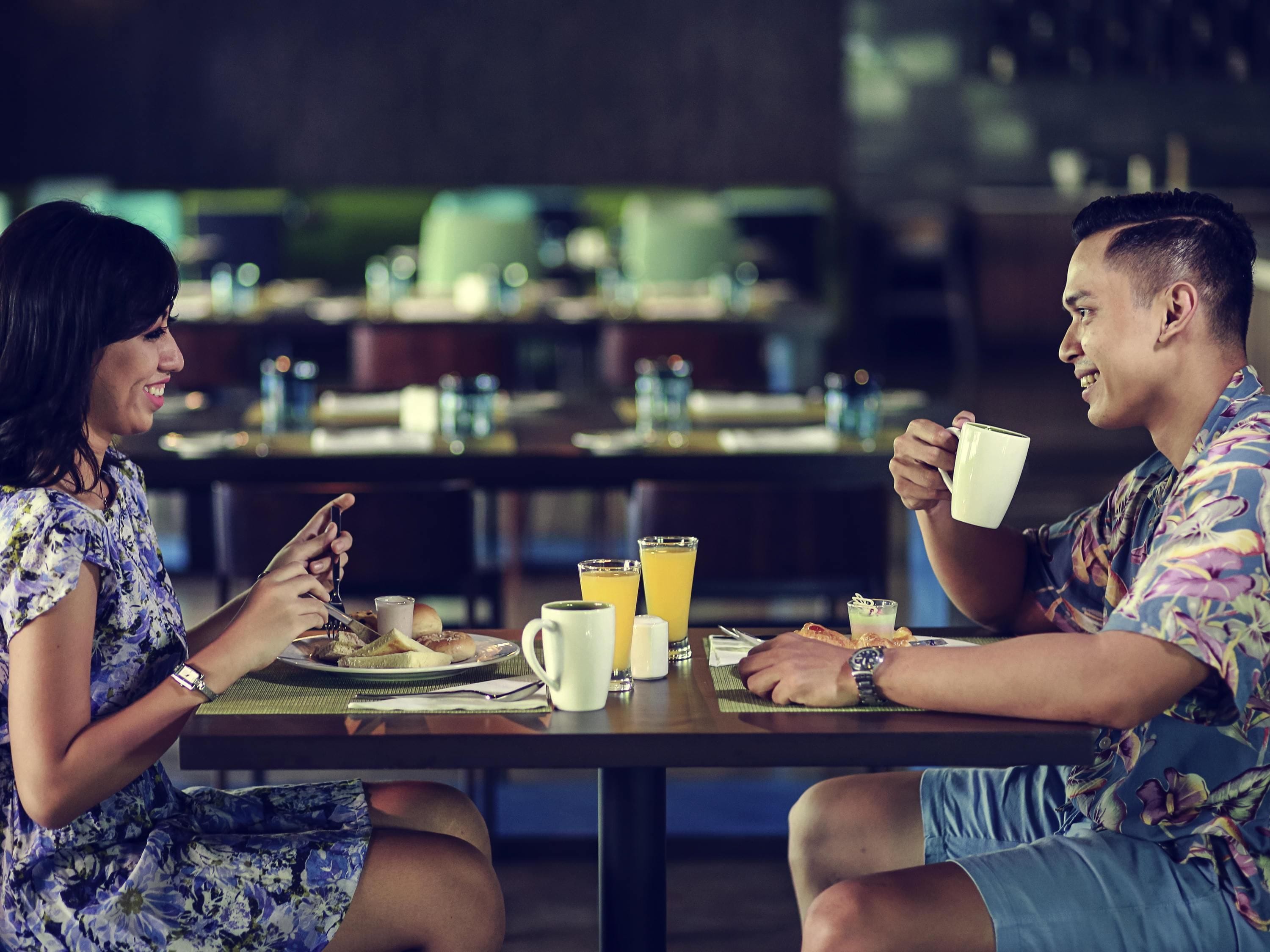 A couple dining at a table with breakfast items and drinks.