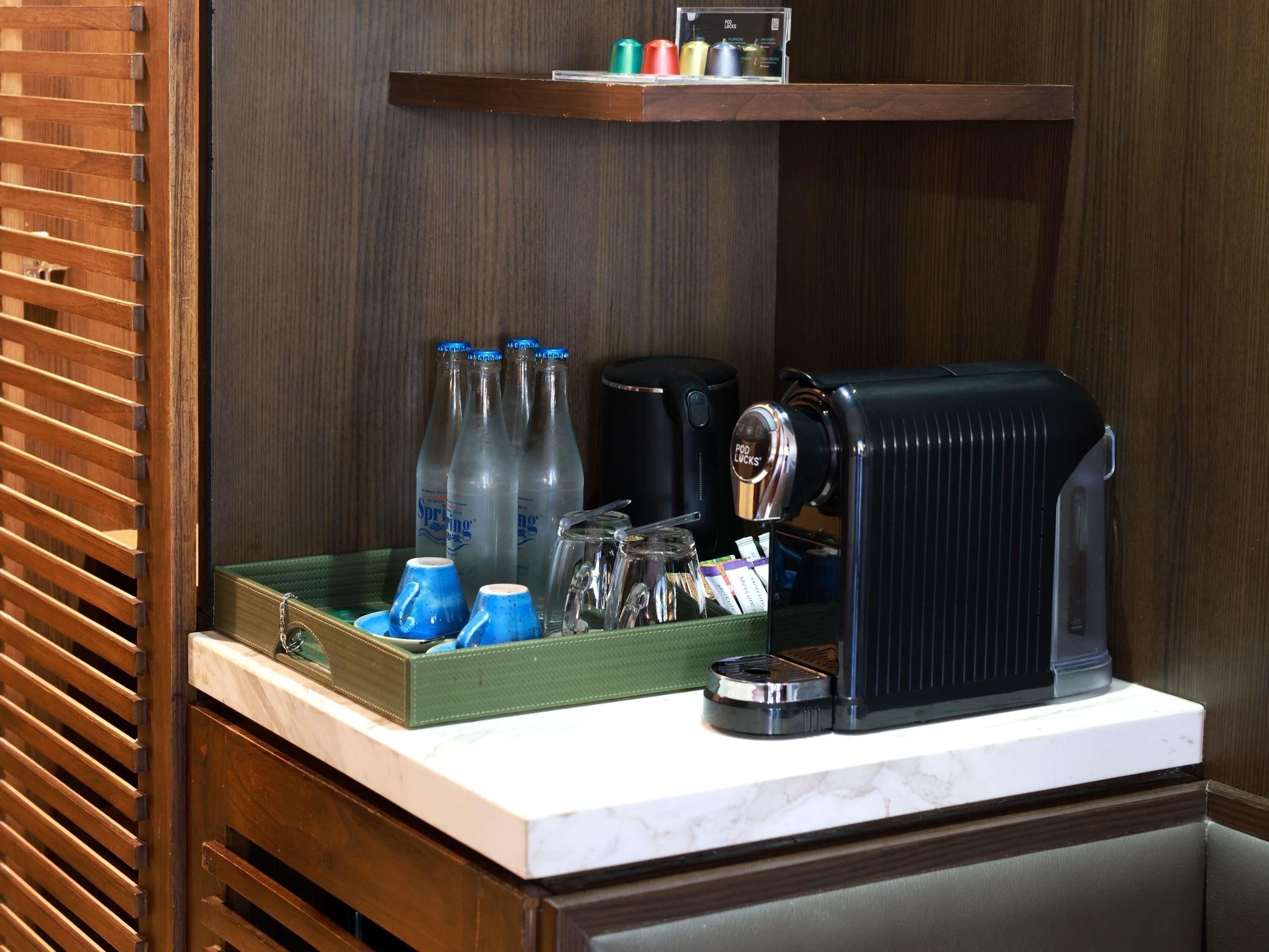 A coffee machine, a tray with blue cups, and bottles of water on a counter.