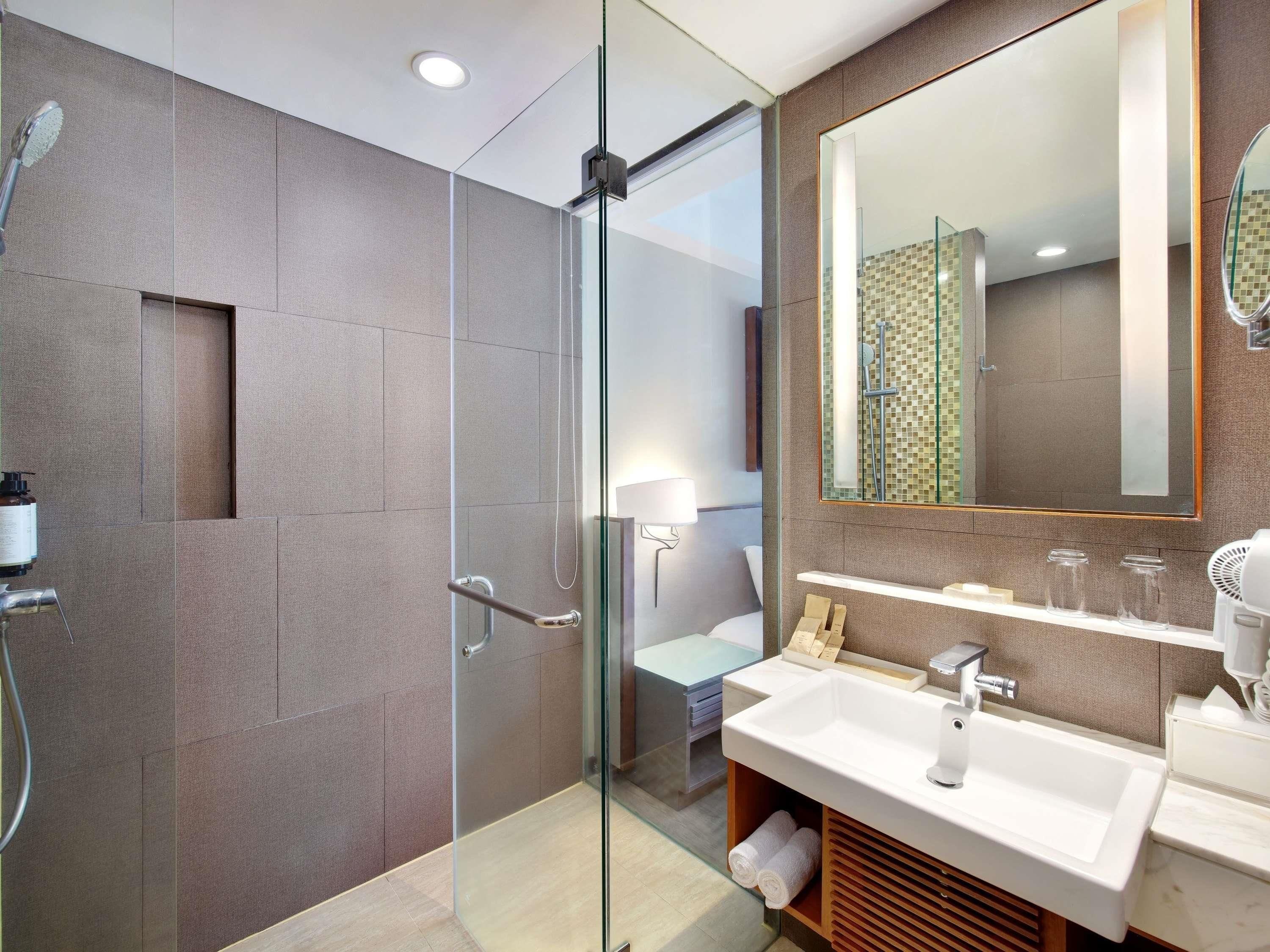 A modern bathroom with a glass-enclosed shower, a large mirror, and a white sink with a vanity.