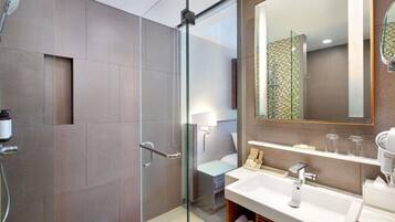 A modern bathroom with a glass-enclosed shower, a large mirror, and a white sink with a vanity.