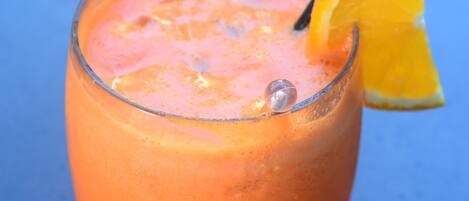 A glass of orange juice with a lemon slice and a straw.