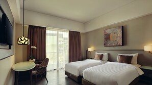 Una habitación de hotel con dos camas, un escritorio, una silla, un televisor y una ventana con cortinas.