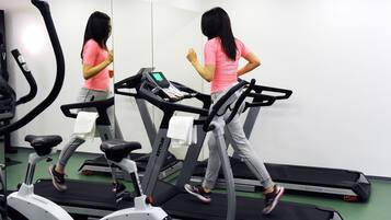 A person using a treadmill in a gym with a mirror and other exercise equipment.