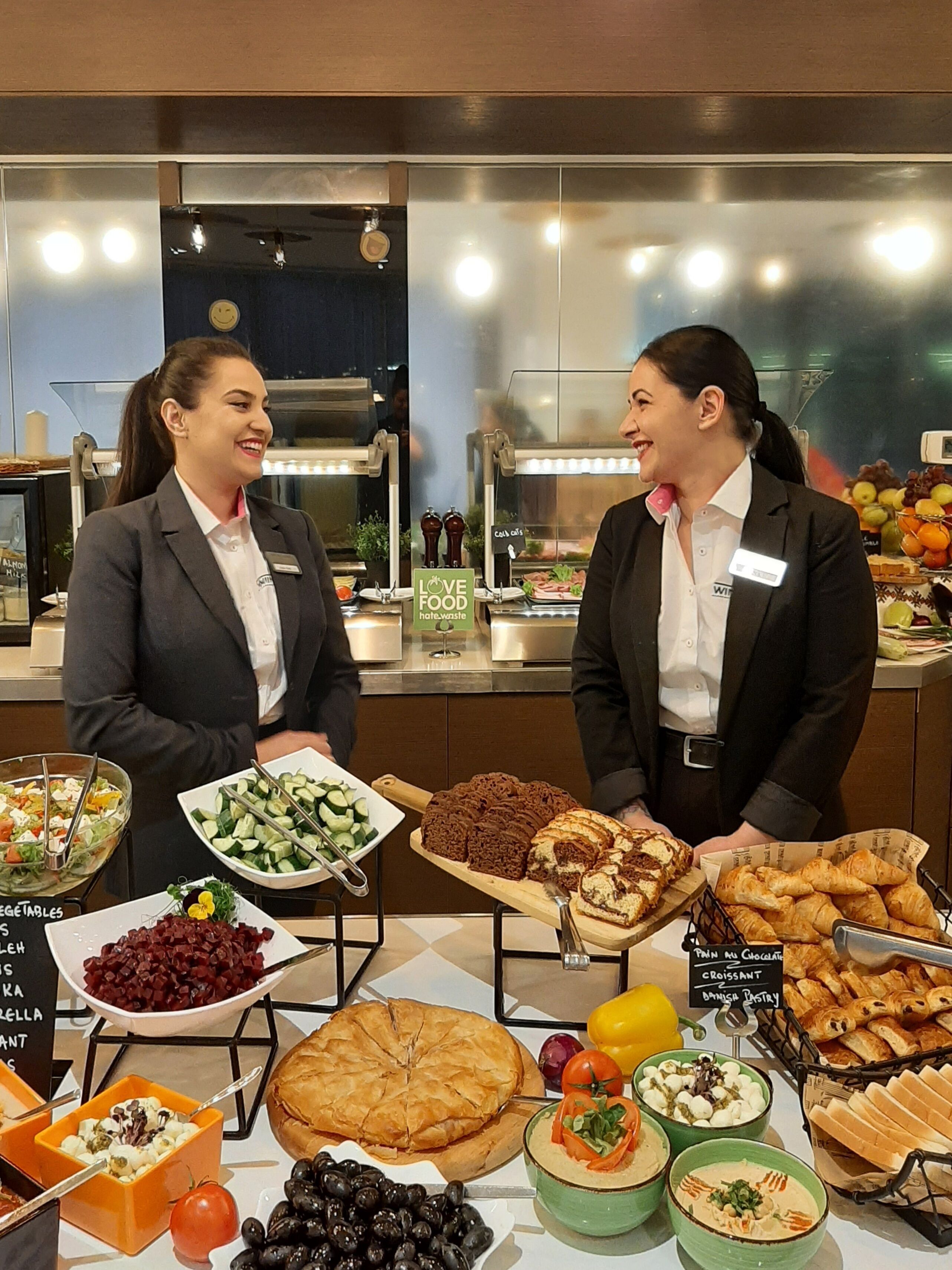 A buffet with various food options including salads, bread, and pastries.