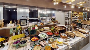 Een buffet met diverse gerechten, een bar en een zithoek met uitzicht over de stad.
