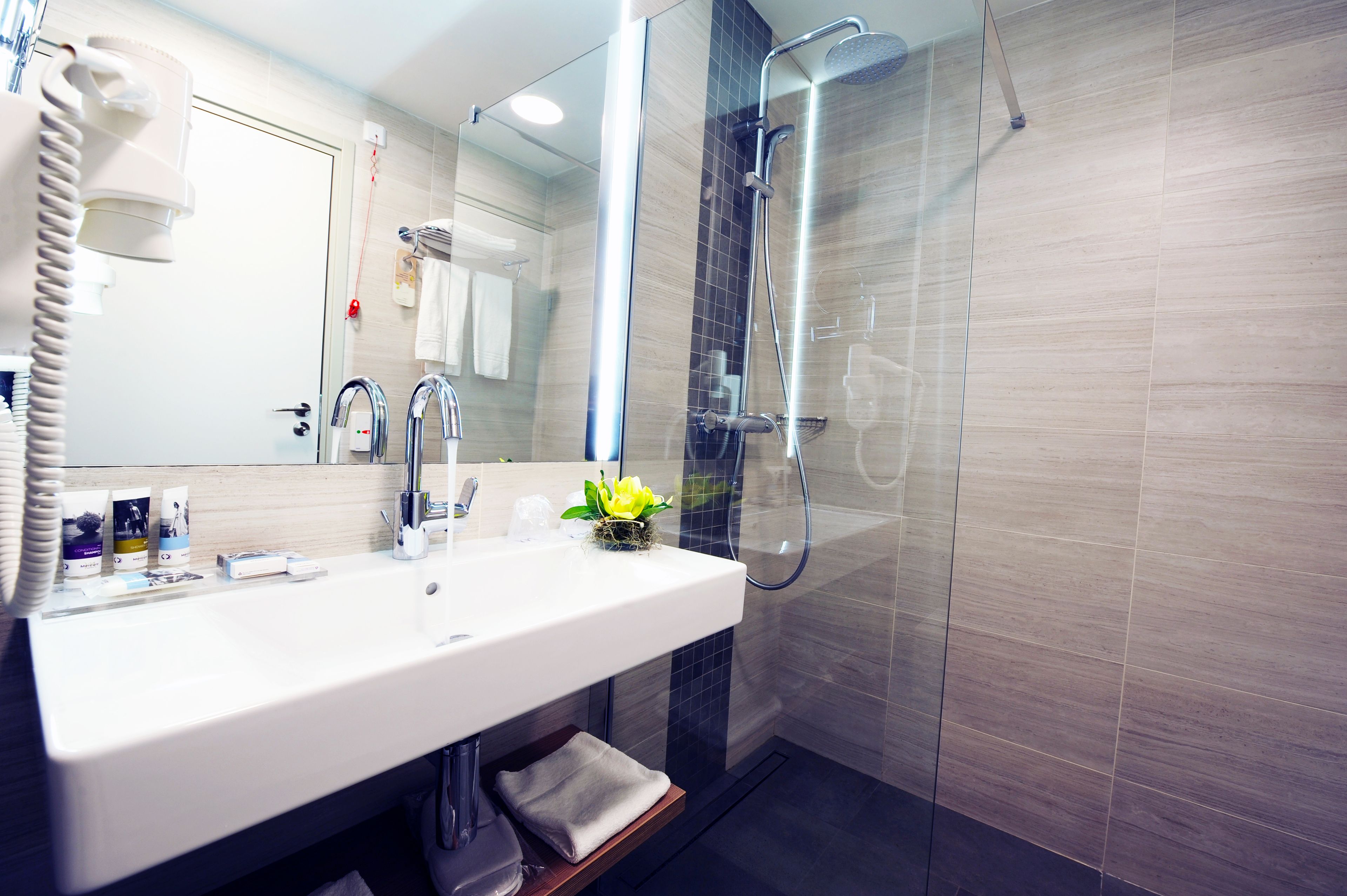 Un baño moderno con un lavabo blanco, una cabina de ducha de cristal y un espejo sobre el lavabo.