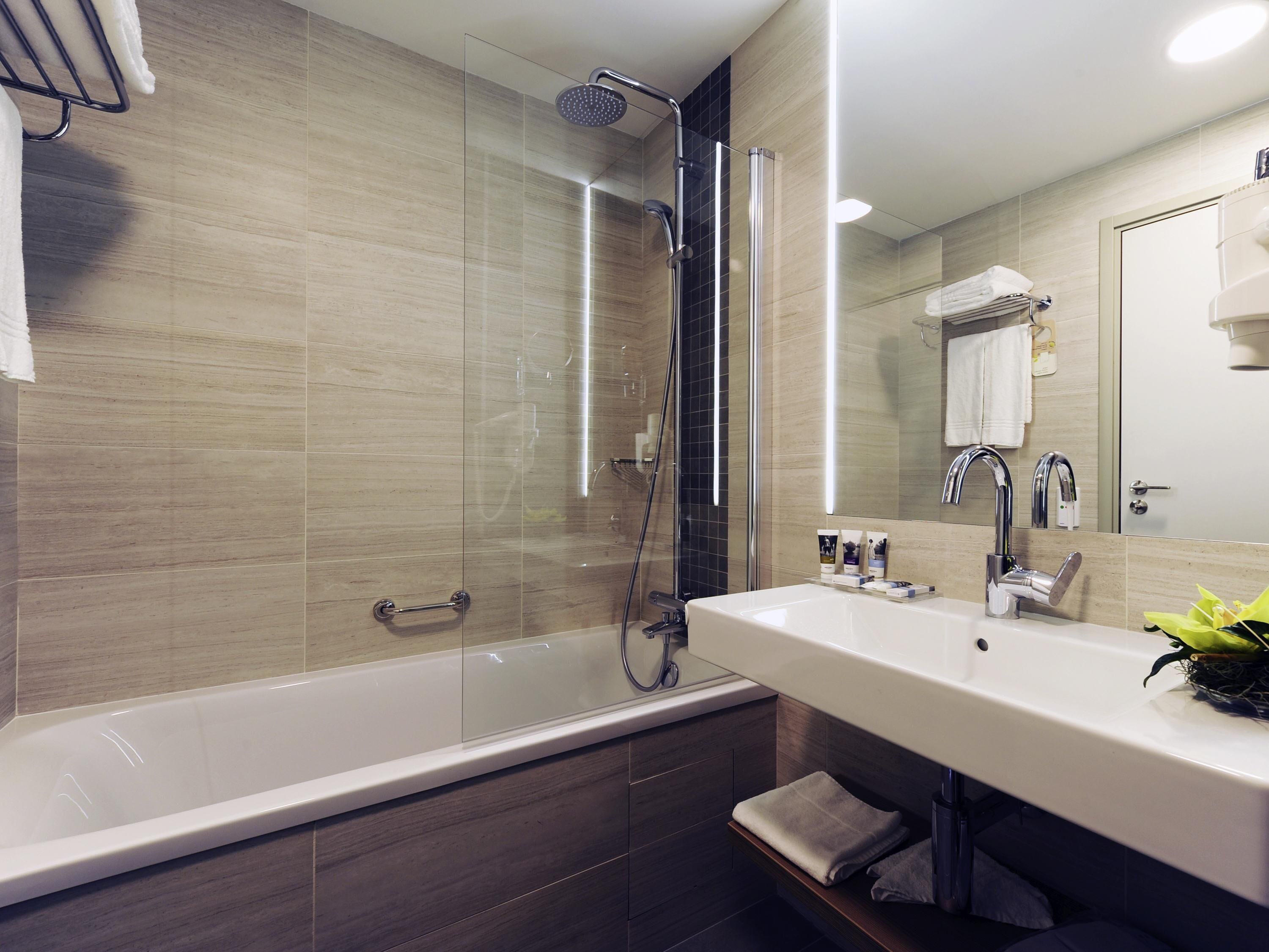 A modern bathroom with a glass-enclosed shower, a white sink, and a mirror.