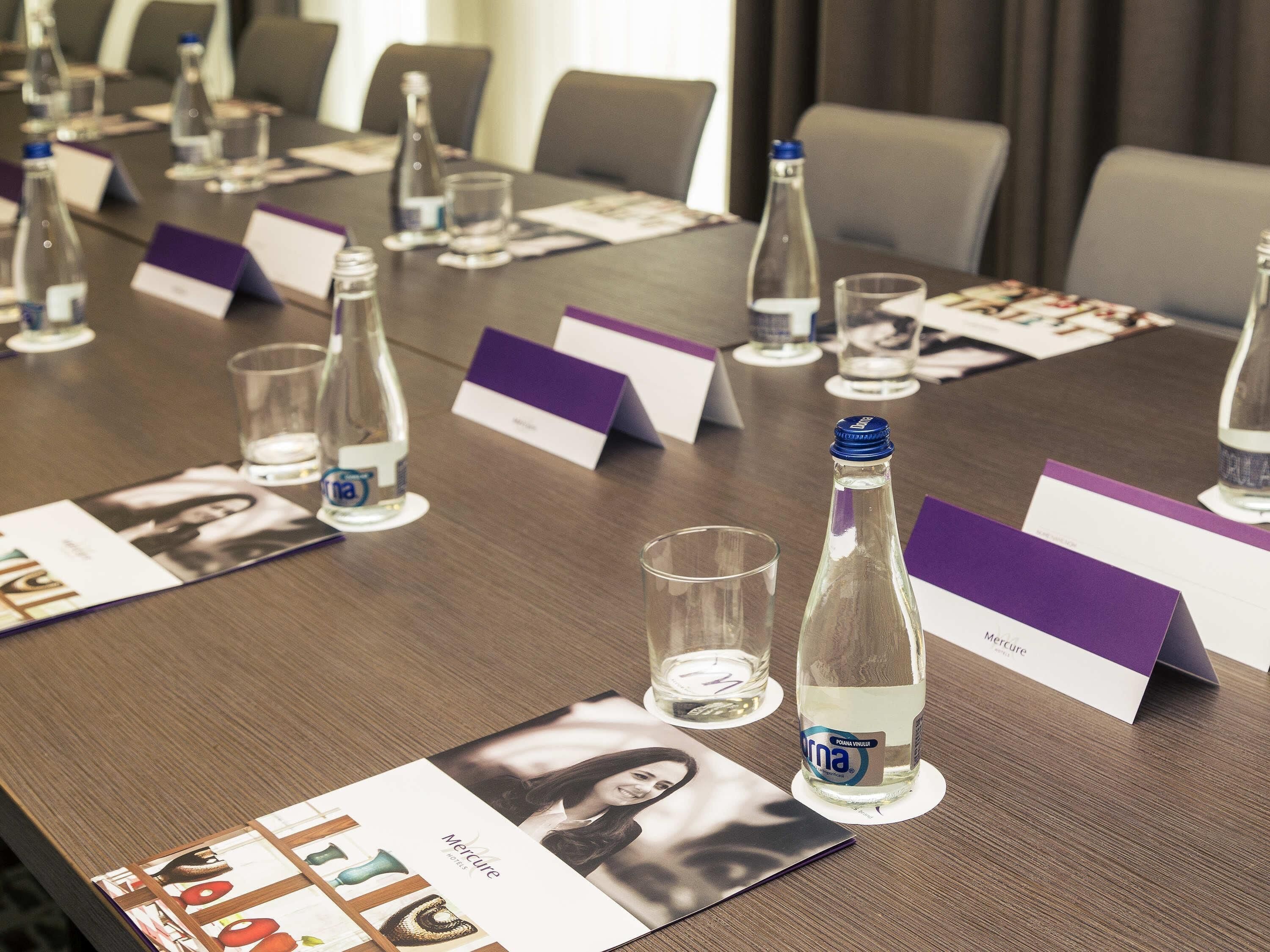 A conference table with name cards, water bottles, and a brochure.