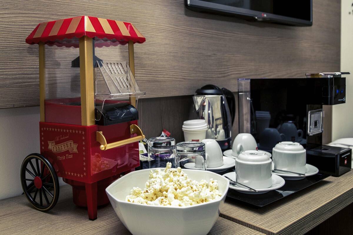 A popcorn cart, a bowl of popcorn, and a coffee machine on a counter.