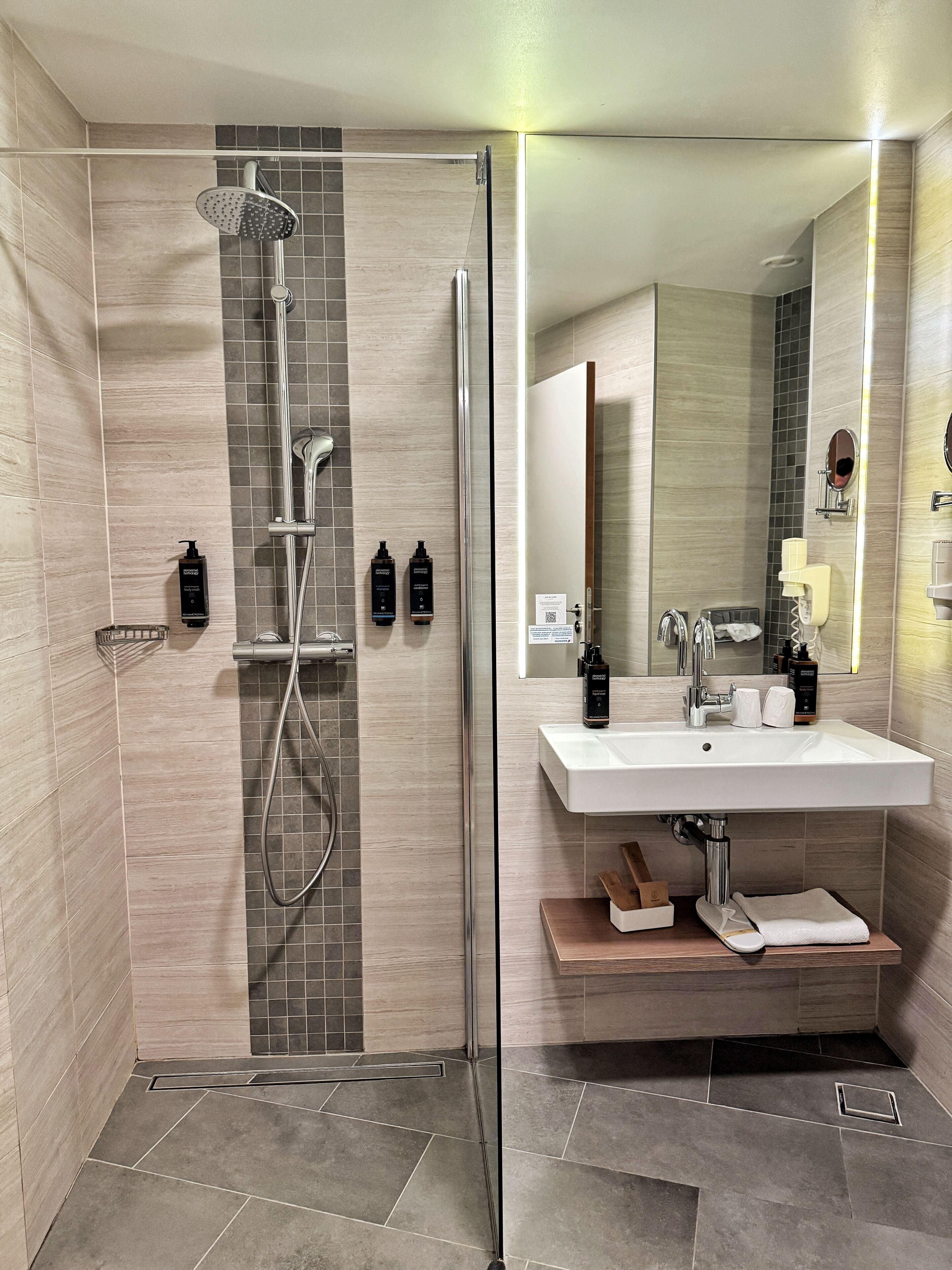 A modern bathroom with a glass-enclosed shower, a white sink, and a mirror.