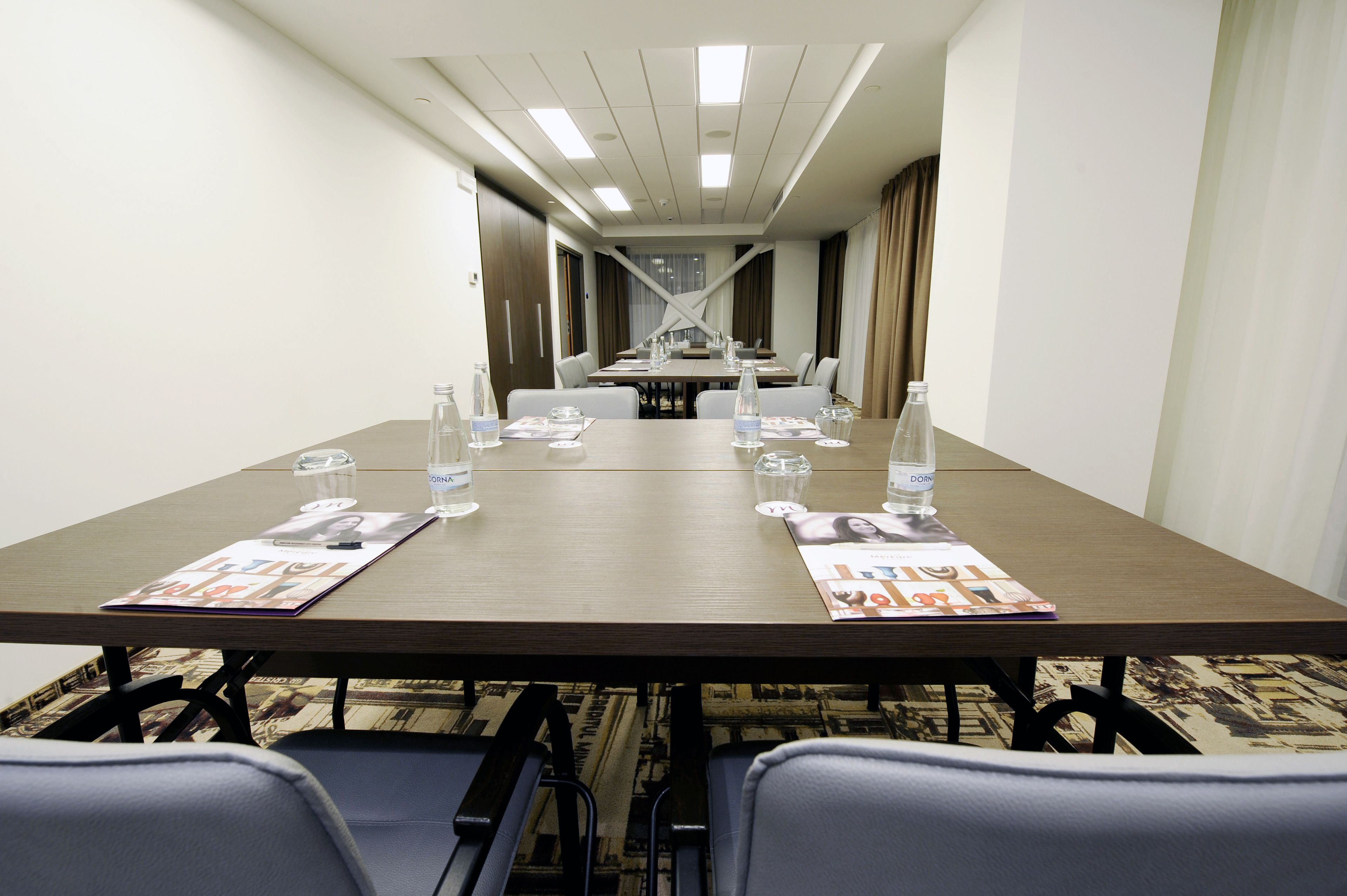 A conference room with a long table, chairs, water bottles, and magazines.