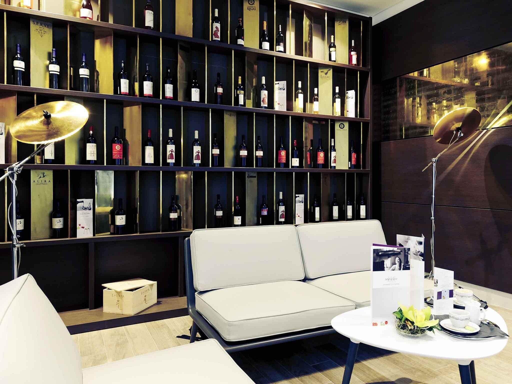 Zona relax moderna con divano, tavolino e parete di bottiglie di vino.