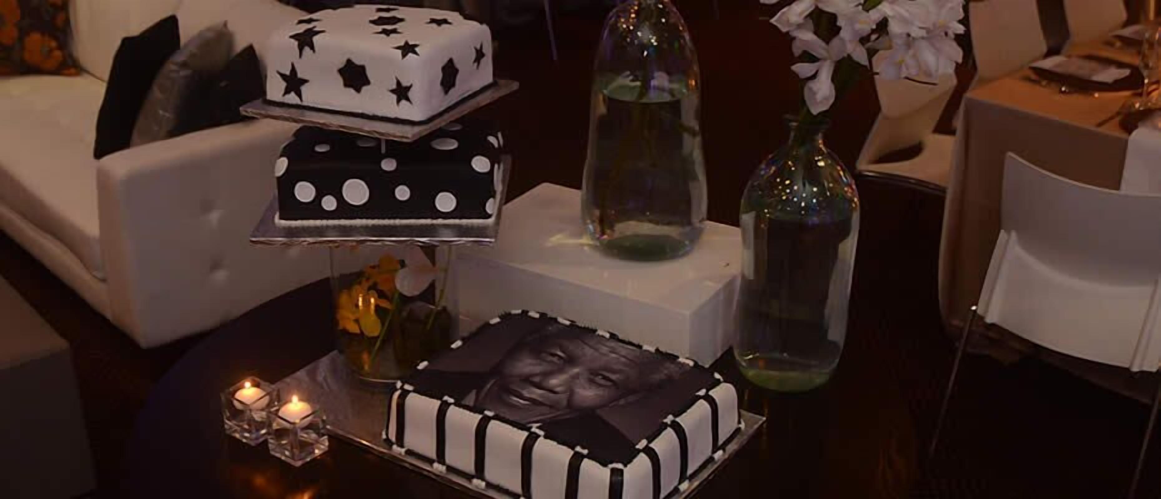 Una mesa con un pastel, velas y un jarrón con flores.