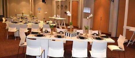 A conference room with round tables, white chairs, and floral centerpieces.