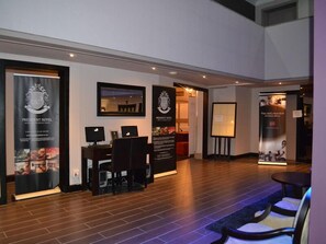 A hotel lobby with a reception desk, seating area, and informational posters. - President Hotel & Conference Venue (Bloemfontein)