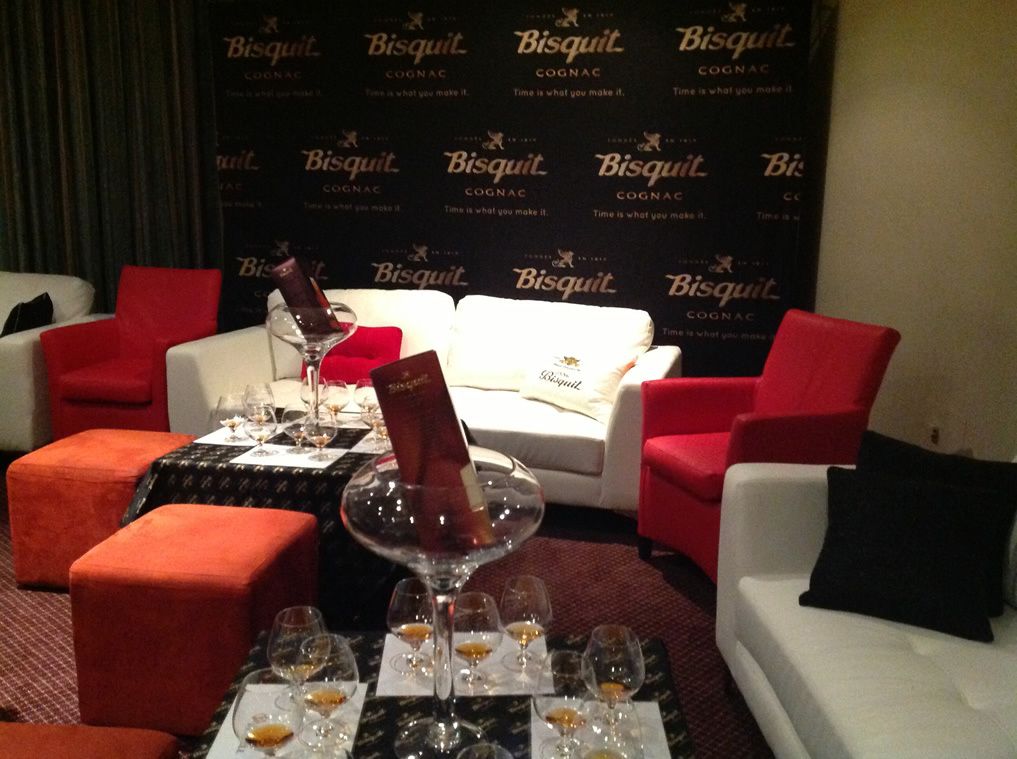 A room with a white sofa set, red chairs, and a table with wine glasses and a bottle.