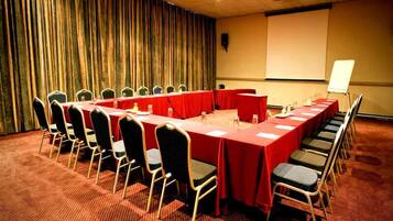 A conference room with a long table, chairs, a projector screen, and a whiteboard.