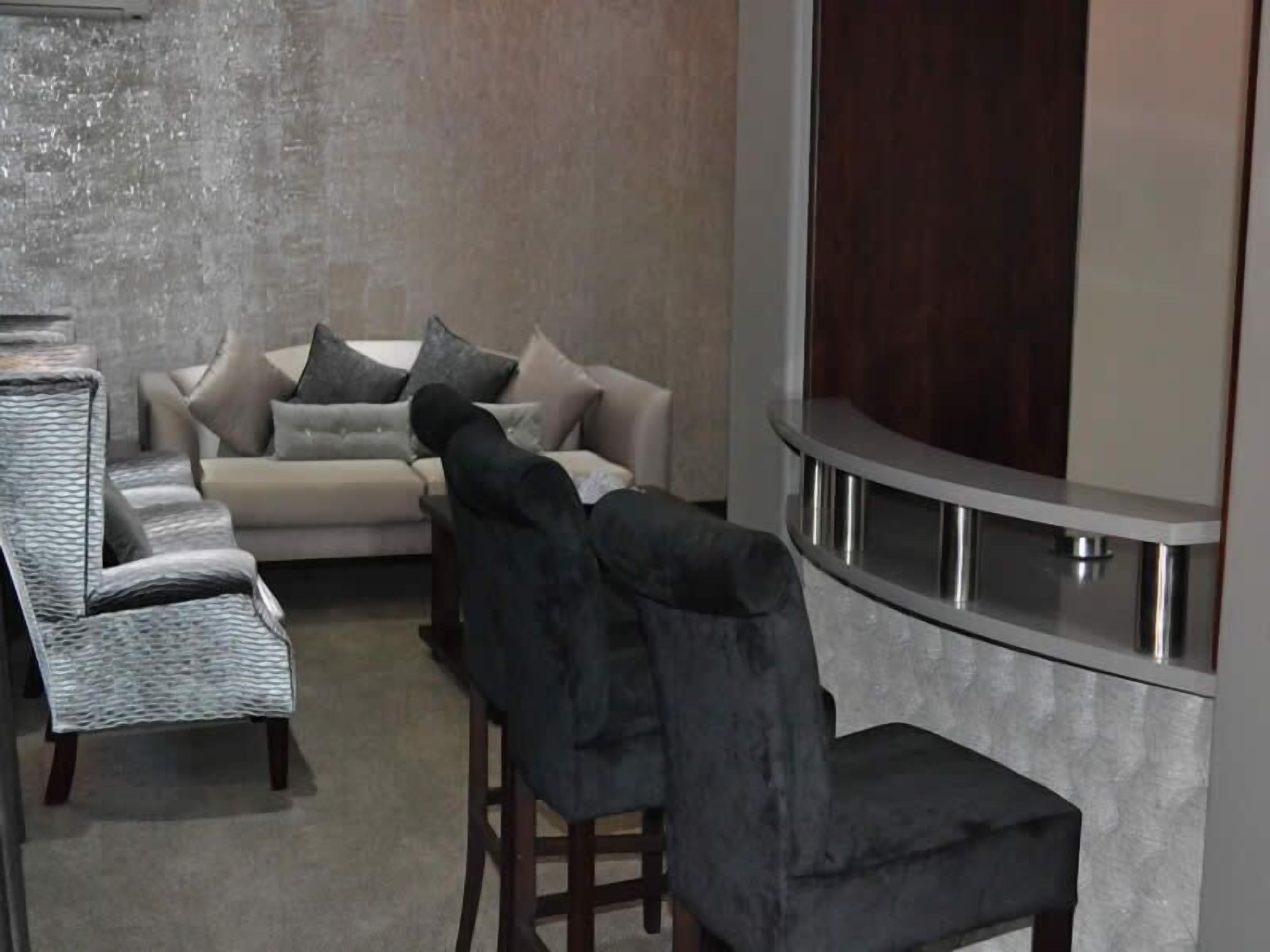Un salon moderne comprenant un canapé, deux fauteuils et une table basse.