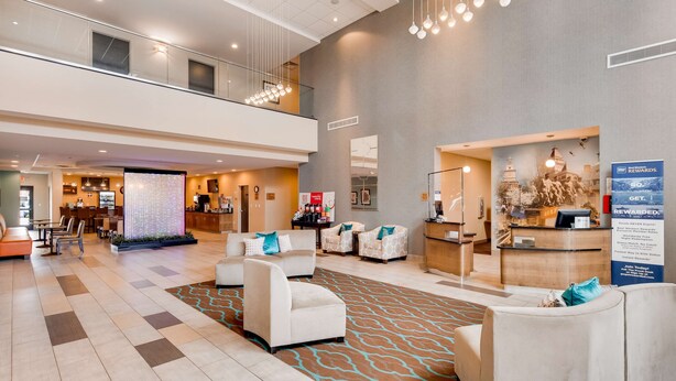 A spacious lobby with a reception desk, seating area, and a view of the kitchen in the background. - Best Western Plus Atrium Inn & Suites (Clarksville)