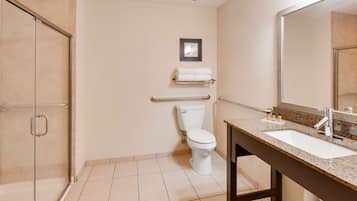 Une salle de bain équipée de toilettes, d’un lavabo, d’un miroir et d’un porte-serviettes.
