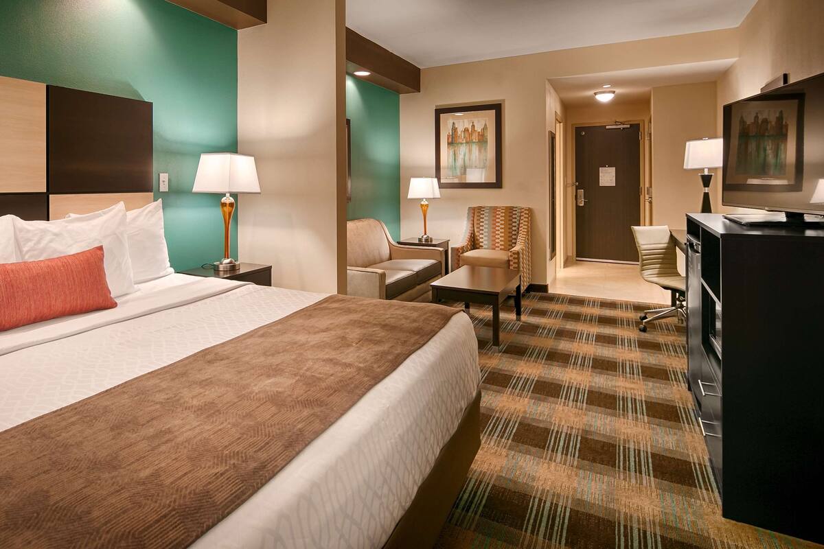 A hotel room with a large bed, a desk, a chair, and a television.