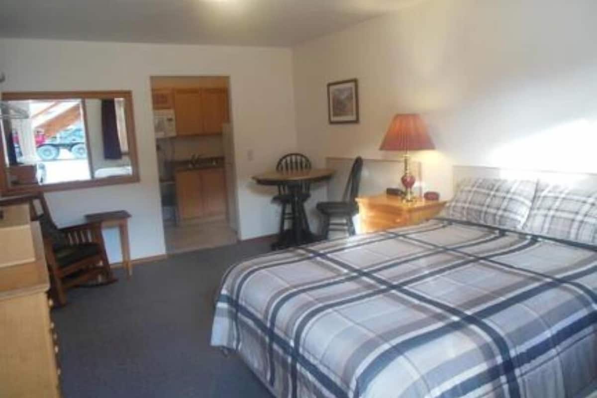 A bedroom with a bed, a desk, a chair, and a lamp.