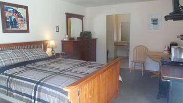 Une chambre à coucher comprenant un lit, une commode, un bureau, une chaise et un miroir.