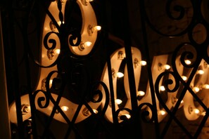 A close-up of a metal gate with intricate designs and illuminated bulbs. - Livetulum (Tulum)