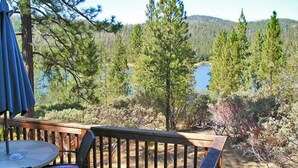 A wooden deck with a table and chairs, overlooking a lake and forested area. - Lake of the Springs RV Resort (Oregon House)