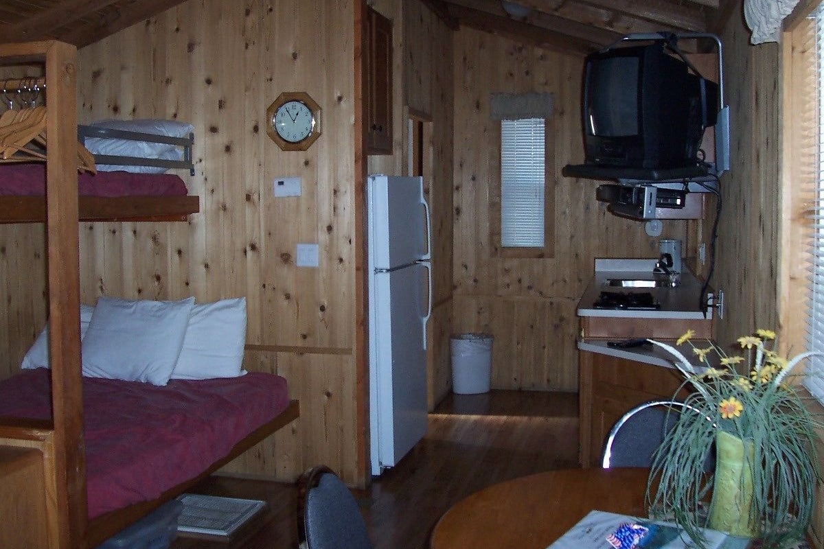 A cabin with bunk beds, a refrigerator, a television, and a small kitchen area.