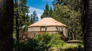 A yurt with a wooden deck and a window, surrounded by trees. - Lake of the Springs RV Resort (Oregon House)