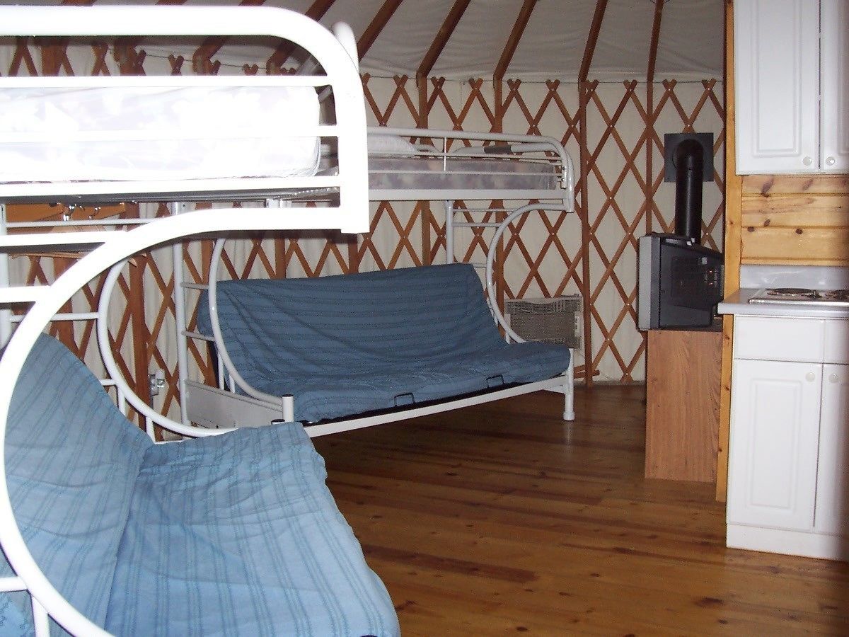 Habitación individual con una cama litera, una kitchenette pequeña y piso de madera.