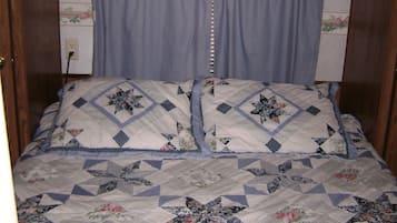 Un dormitorio con una cama cubierta por un edredón floral, un cabecero de madera y una ventana con vidrios decorativos.