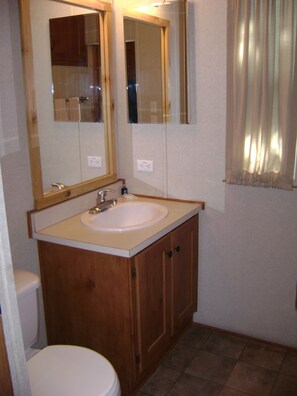 A bathroom with a wooden vanity, a sink, a mirror, and a toilet.