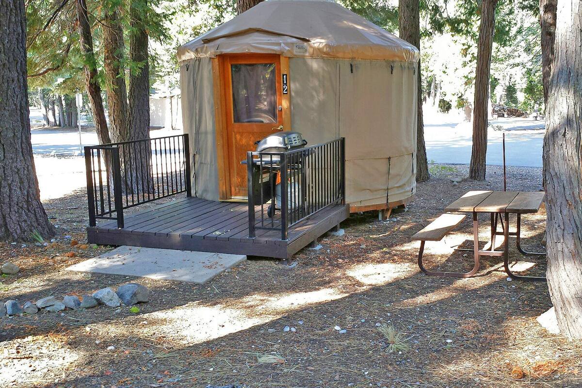 A small, single-story cabin with a wooden deck and a picnic table.