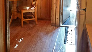 A wooden interior with a table, chair, lamp, and a refrigerator. - Snowflower RV Resort (Emigrant Gap)
