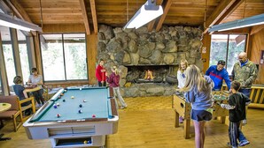 A pool table in a room with stone walls and a fireplace. - Snowflower RV Resort (Emigrant Gap)