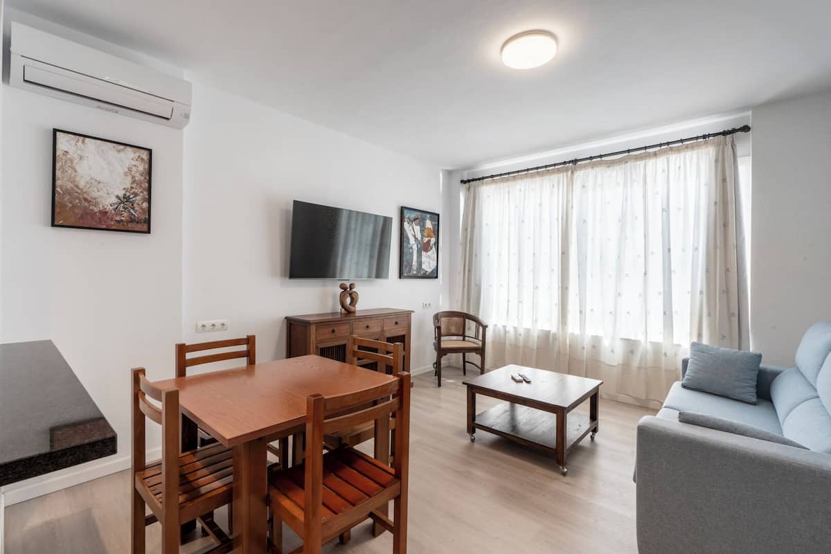 A modern living room with a dining table, sofa, and TV.