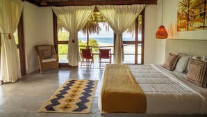 Una habitación con cama, una silla, una mesa y vista al océano.