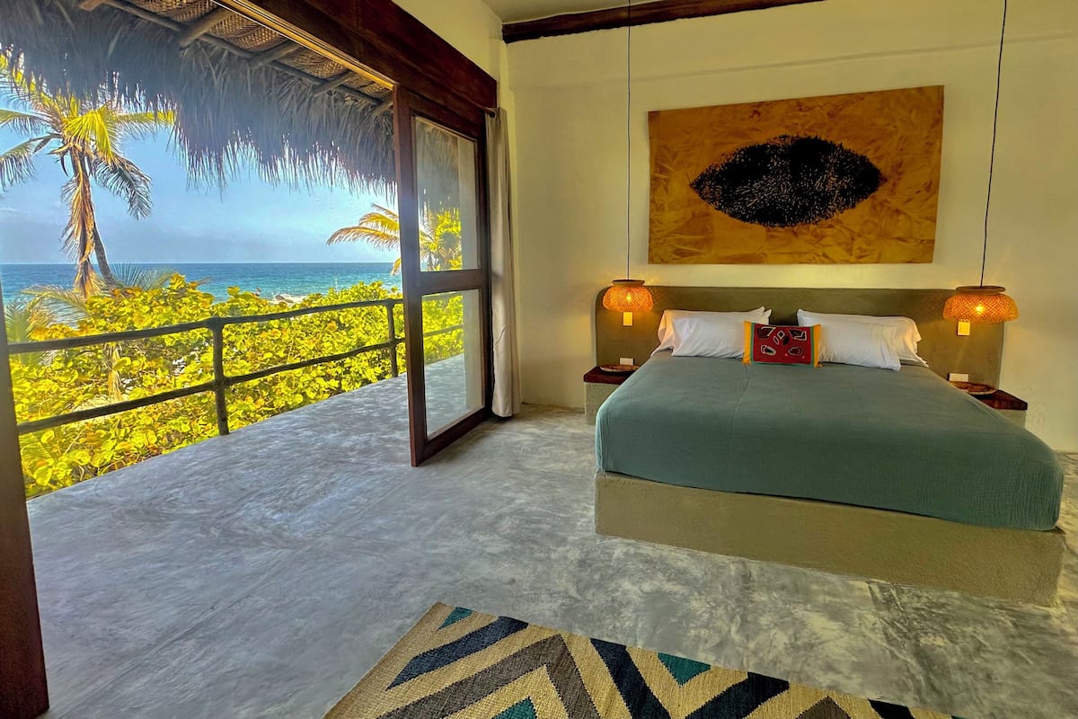 Un dormitorio con una cama grande, vistas al océano y un ambiente tropical.