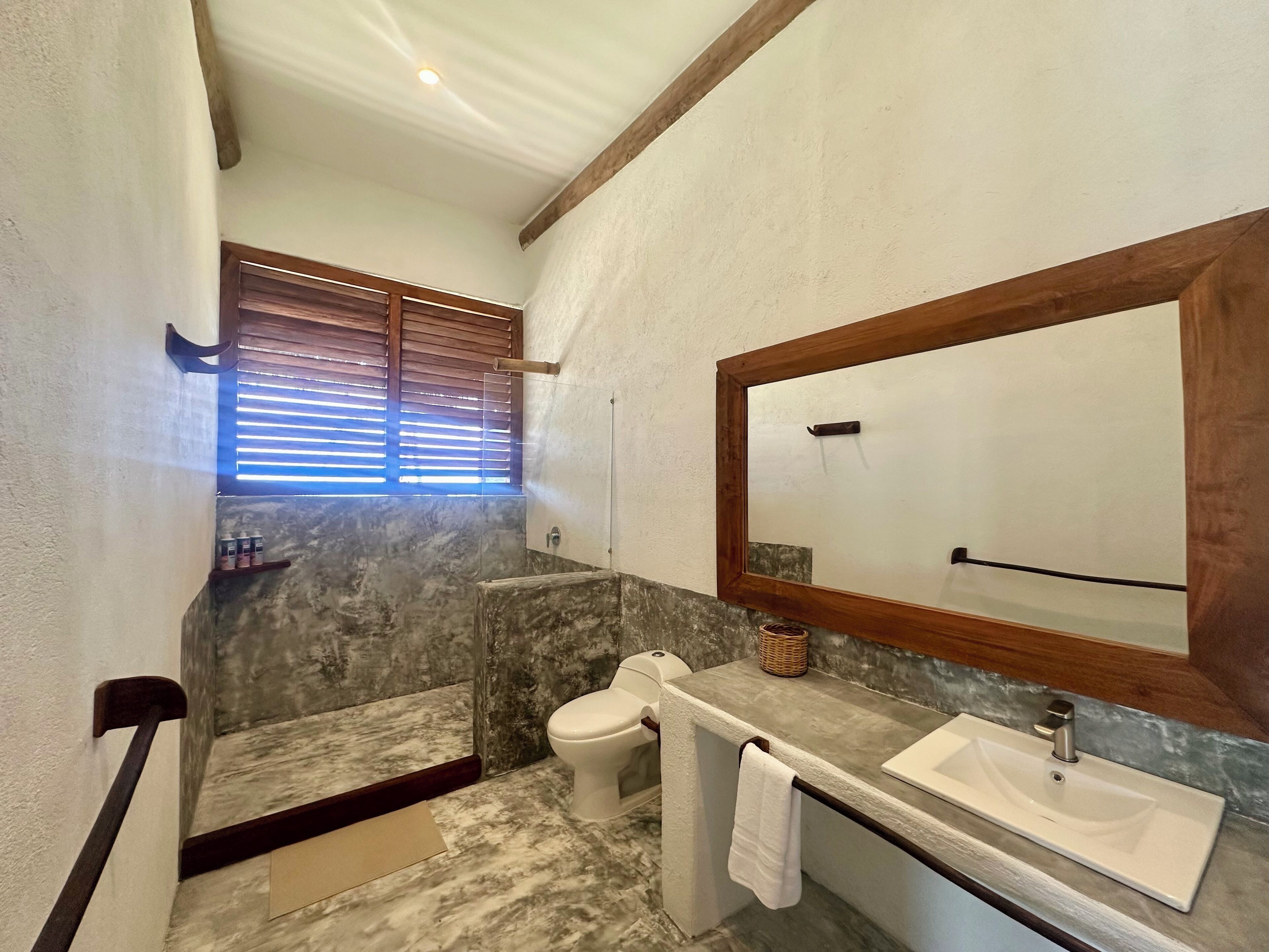 A bathroom with a marble floor, a white sink, a toilet, and a large mirror with a wooden frame.